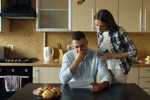 Family reviewing household bills and assistance paperwork together at a kitchen table.